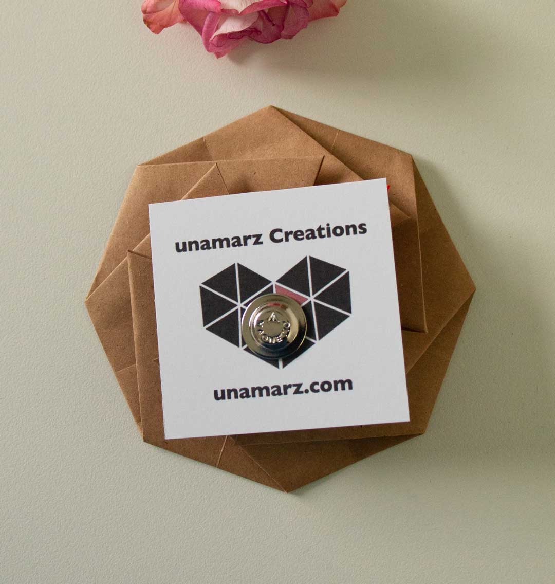 Pin on a hexagonal brown card with 'unamarz Creations' branding, against a light background.