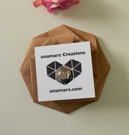 Pin on a hexagonal brown card with 'unamarz Creations' branding, against a light background.